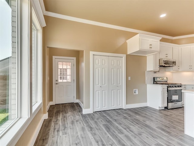 kitchen featuring white cabinetry, stainless steel range with gas cooktop, crown molding, and light hardwood / wood-style floors