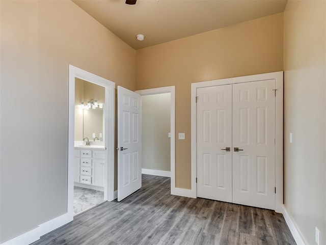 unfurnished bedroom featuring wood-type flooring, ensuite bath, and a closet