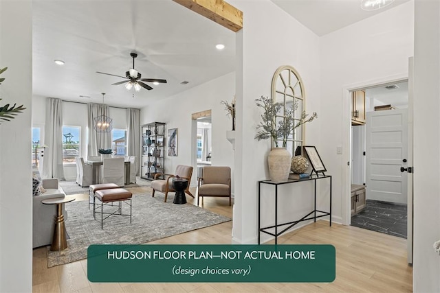 living room featuring ceiling fan with notable chandelier and light hardwood / wood-style floors