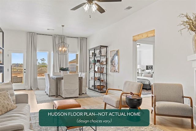 living room with ceiling fan with notable chandelier and light hardwood / wood-style floors