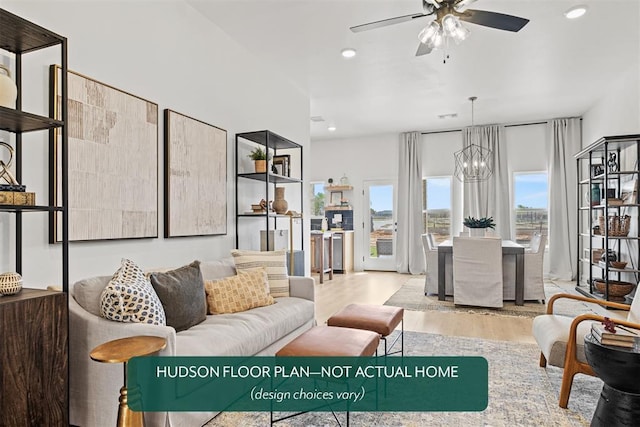 living room with ceiling fan with notable chandelier and light wood-type flooring