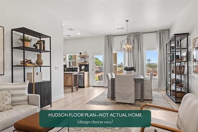 dining area featuring an inviting chandelier, sink, light hardwood / wood-style floors, and a healthy amount of sunlight