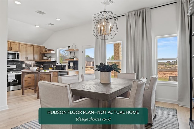 dining area featuring sink, a chandelier, vaulted ceiling, and light hardwood / wood-style flooring