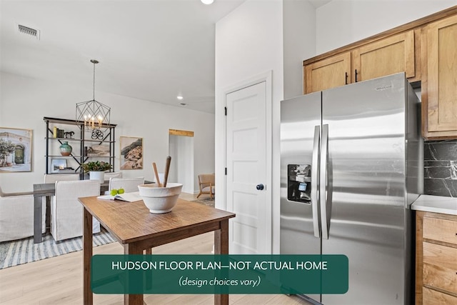 kitchen featuring decorative light fixtures, decorative backsplash, stainless steel fridge with ice dispenser, an inviting chandelier, and light hardwood / wood-style flooring