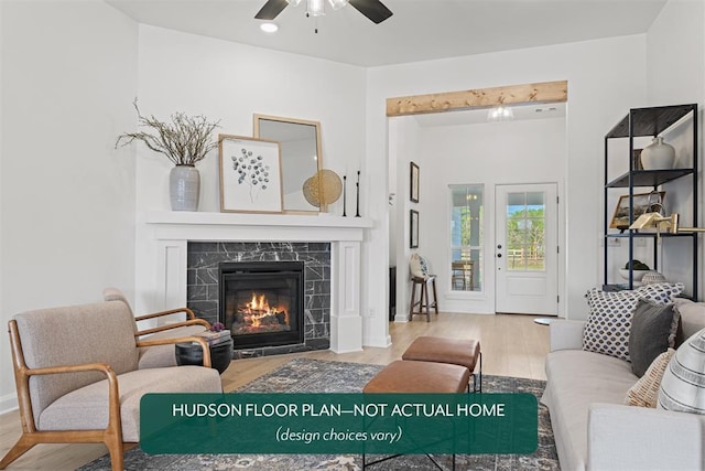 living room featuring a premium fireplace, hardwood / wood-style floors, and ceiling fan