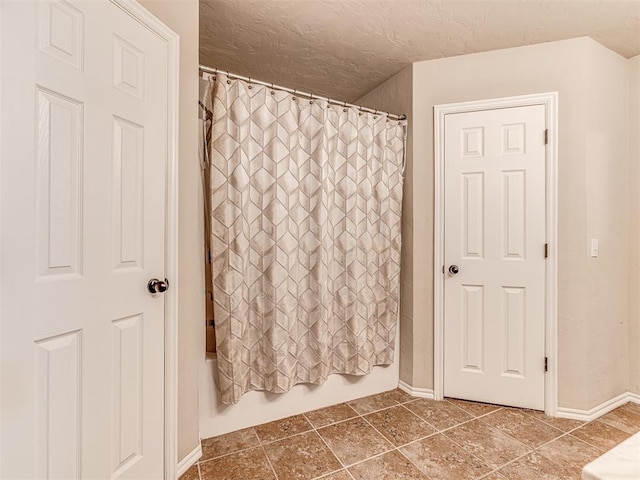 bathroom with shower / bathtub combination with curtain and a textured ceiling