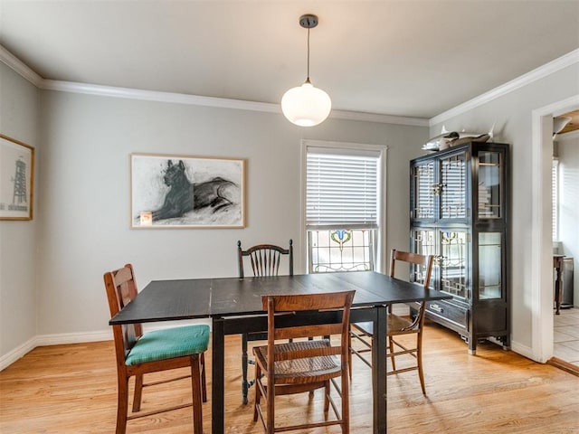 dining space with ornamental molding and light hardwood / wood-style flooring