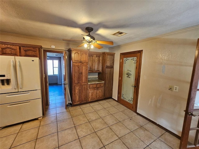 kitchen with light tile patterned flooring, ornamental molding, a textured ceiling, and white fridge with ice dispenser