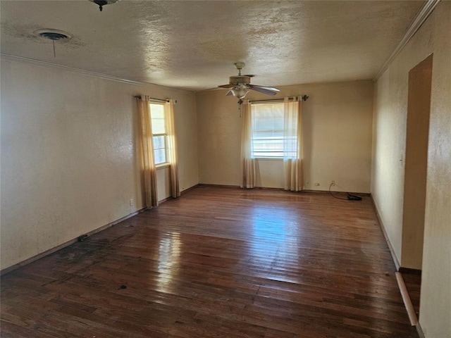 unfurnished room featuring dark wood-type flooring, ornamental molding, a textured ceiling, and plenty of natural light