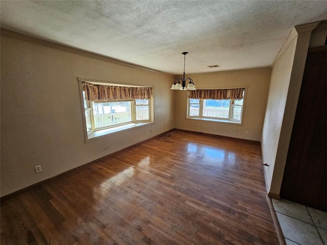 unfurnished dining area with an inviting chandelier, hardwood / wood-style flooring, ornamental molding, and a textured ceiling