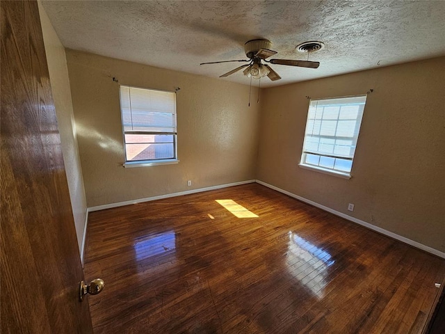 unfurnished room featuring a healthy amount of sunlight, wood-type flooring, and a textured ceiling