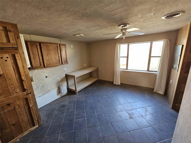 interior space with dark tile patterned flooring, a textured ceiling, and ceiling fan