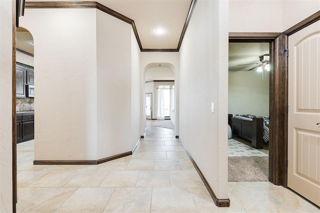 corridor featuring light tile patterned floors and crown molding