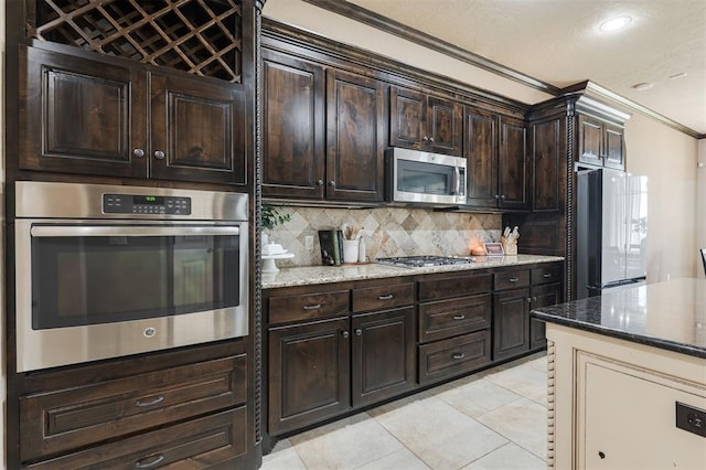 kitchen with backsplash, light tile patterned floors, stainless steel appliances, crown molding, and dark brown cabinets