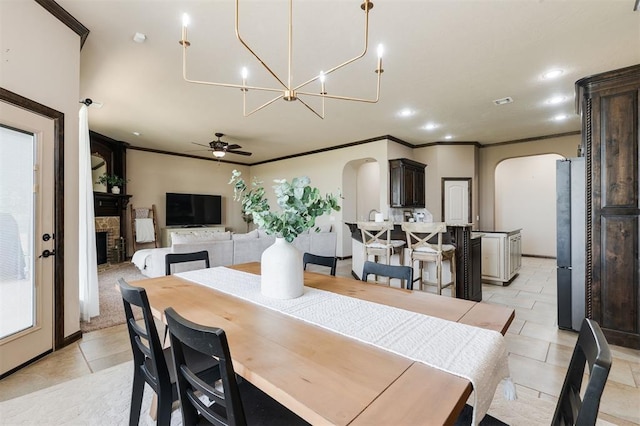 tiled dining area featuring crown molding, ceiling fan, and a fireplace