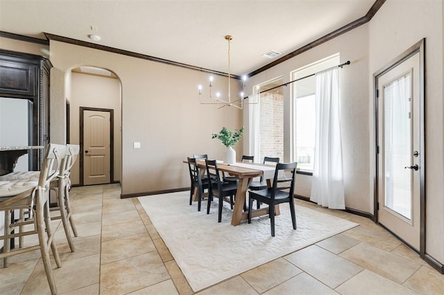 tiled dining room with ornamental molding and a chandelier