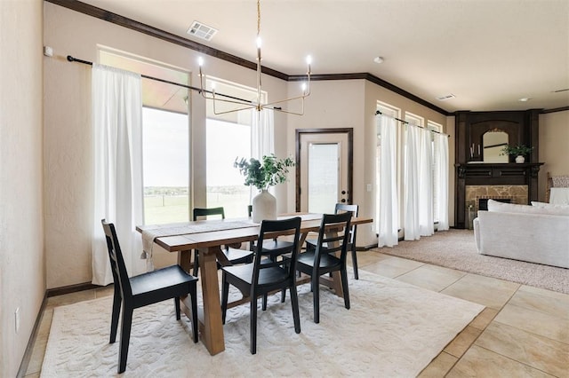 dining space featuring ornamental molding, a stone fireplace, a chandelier, and light tile patterned floors