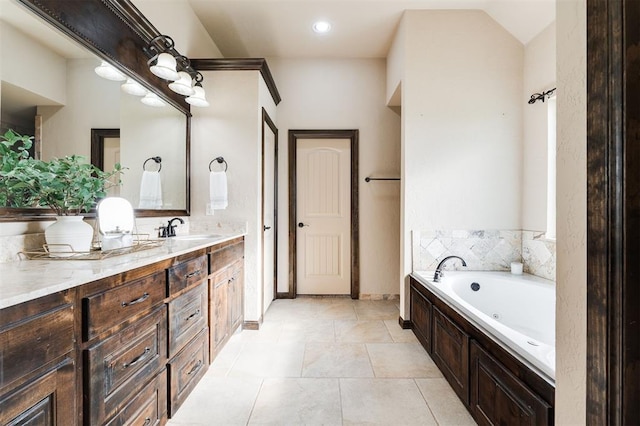 bathroom with a washtub, vanity, and tile patterned floors