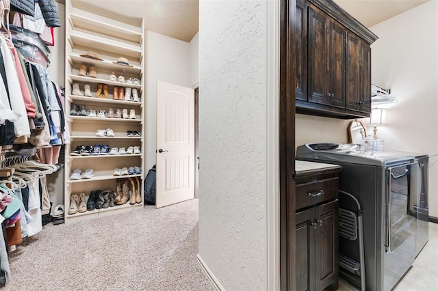 washroom featuring cabinets, washer and dryer, and light carpet