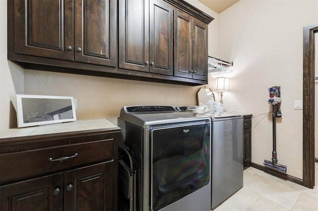 washroom with cabinets, washer and dryer, and light tile patterned floors