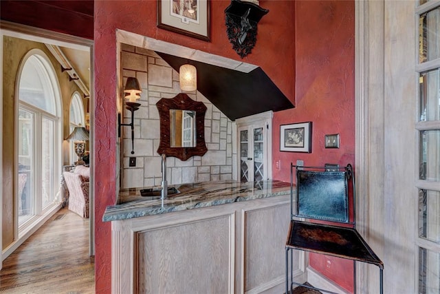 bar featuring tasteful backsplash, sink, light stone counters, and light hardwood / wood-style flooring