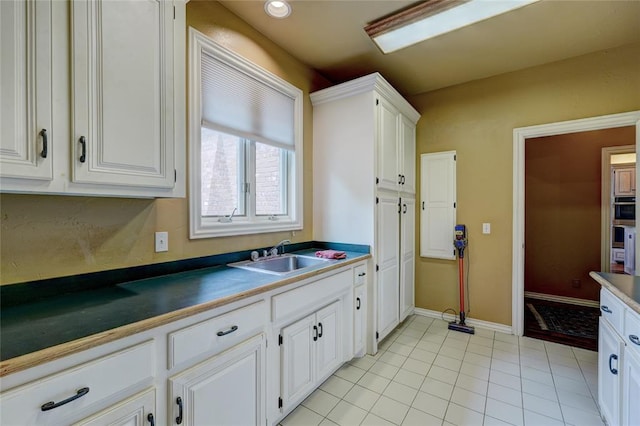 kitchen featuring sink, light tile patterned floors, and white cabinets