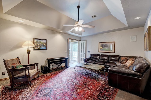 living room featuring ceiling fan and a raised ceiling