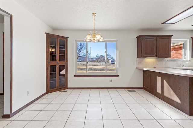 unfurnished dining area with a textured ceiling, a chandelier, and light tile patterned flooring