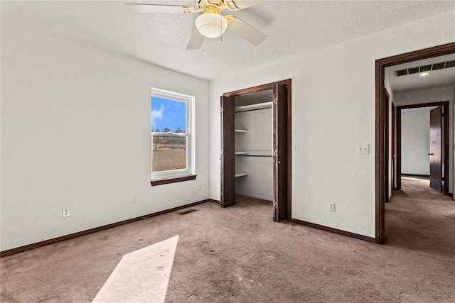 unfurnished bedroom featuring light carpet, ceiling fan, a closet, and a textured ceiling