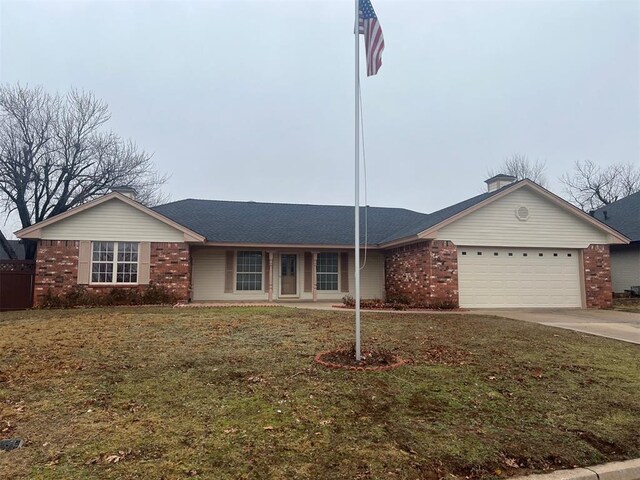 ranch-style home featuring an attached garage, driveway, a front lawn, and brick siding