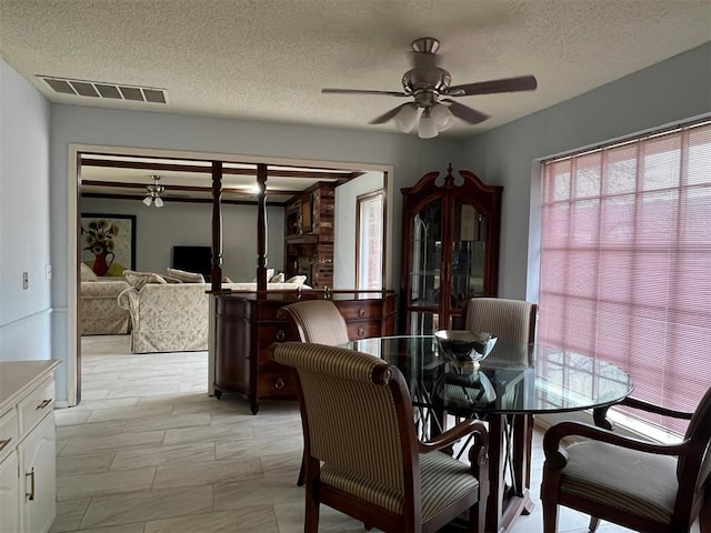 dining space with a textured ceiling, visible vents, and a ceiling fan