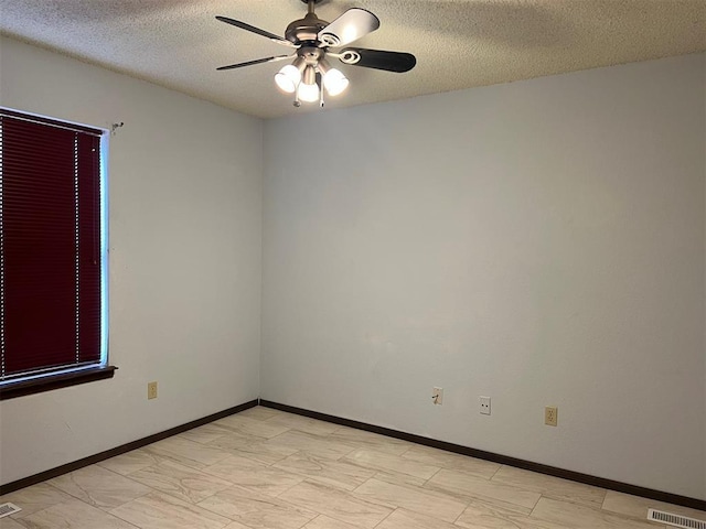 unfurnished room with ceiling fan, a textured ceiling, visible vents, and baseboards