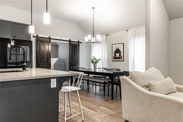 kitchen featuring pendant lighting, lofted ceiling, sink, a kitchen bar, and a barn door