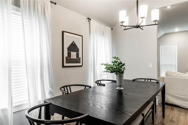 dining area featuring hardwood / wood-style flooring, vaulted ceiling, and a notable chandelier