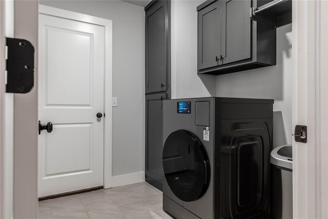 clothes washing area featuring cabinets, washer / clothes dryer, and light tile patterned floors