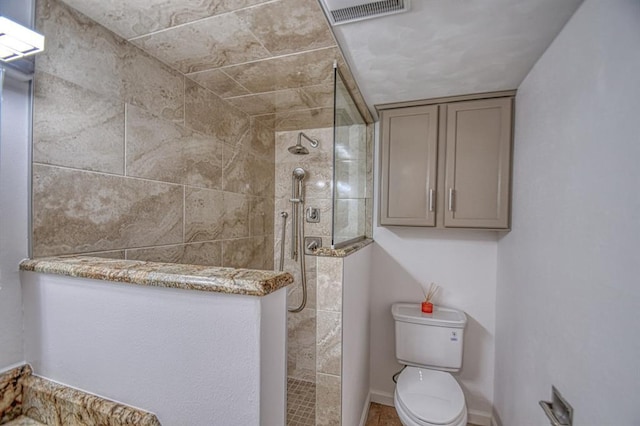 bathroom featuring a tile shower and toilet