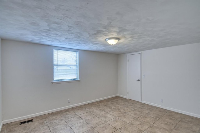 unfurnished room with light tile patterned floors and a textured ceiling