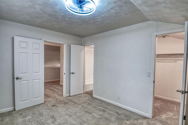 unfurnished bedroom featuring vaulted ceiling, a walk in closet, light colored carpet, and a closet