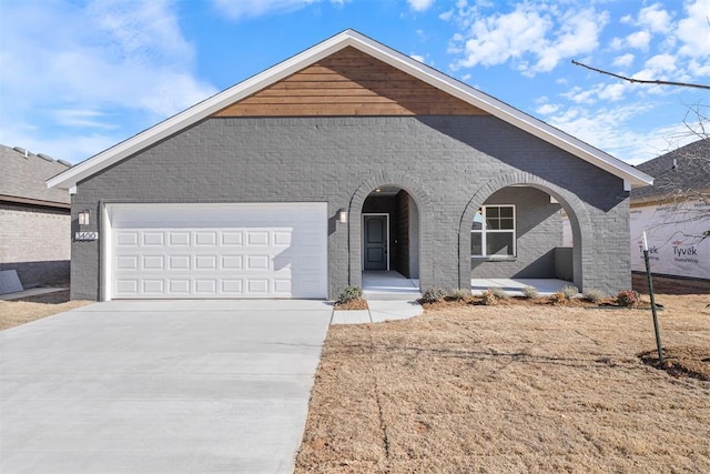 view of front of home with driveway, a porch, an attached garage, and brick siding