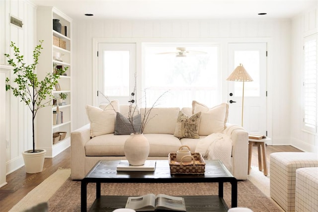 living room featuring hardwood / wood-style flooring, built in features, and ceiling fan