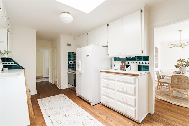 kitchen with hardwood / wood-style flooring, white cabinetry, white fridge with ice dispenser, and an inviting chandelier