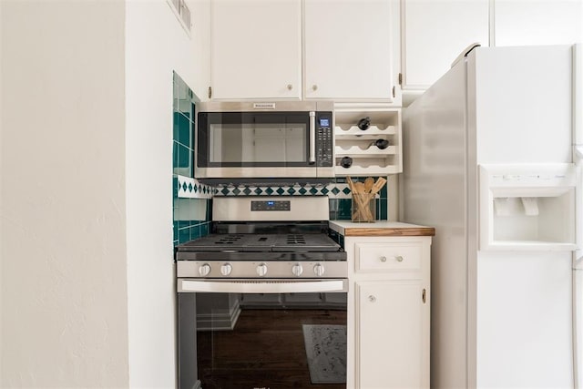 kitchen featuring stainless steel appliances, white cabinetry, hardwood / wood-style floors, and decorative backsplash