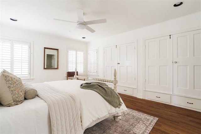 bedroom featuring dark hardwood / wood-style flooring, two closets, and ceiling fan