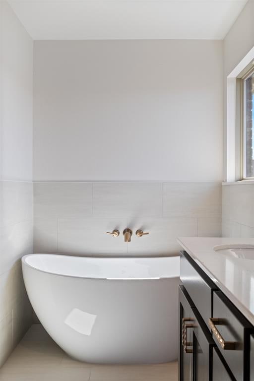 bathroom featuring wainscoting, tile walls, a freestanding bath, and vanity