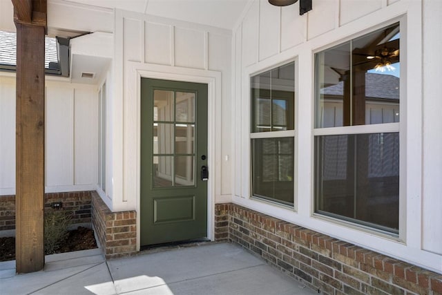 entrance to property with visible vents, board and batten siding, and brick siding