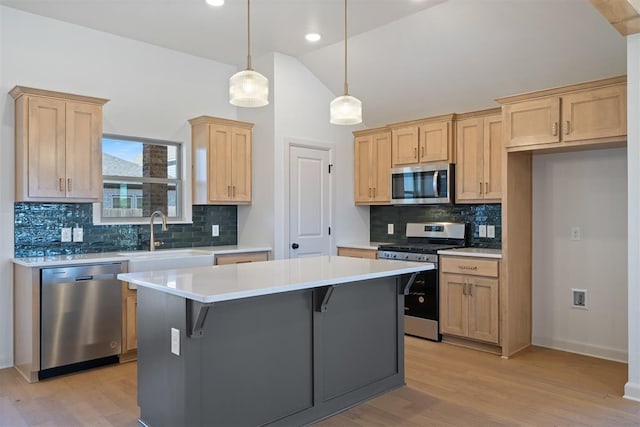 kitchen featuring a center island, stainless steel appliances, light countertops, light brown cabinetry, and vaulted ceiling