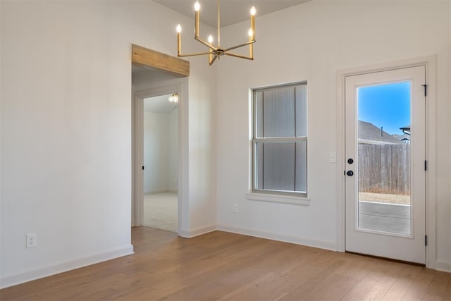 entryway featuring an inviting chandelier, wood finished floors, and baseboards