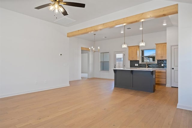 kitchen featuring a breakfast bar area, light wood-style flooring, open floor plan, light countertops, and decorative backsplash