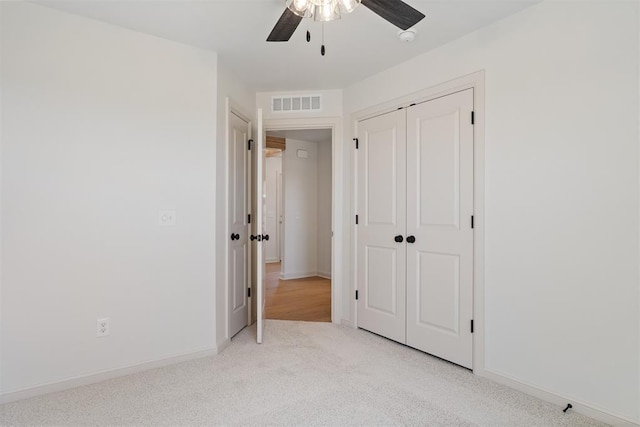 unfurnished bedroom with baseboards, visible vents, a ceiling fan, light colored carpet, and a closet