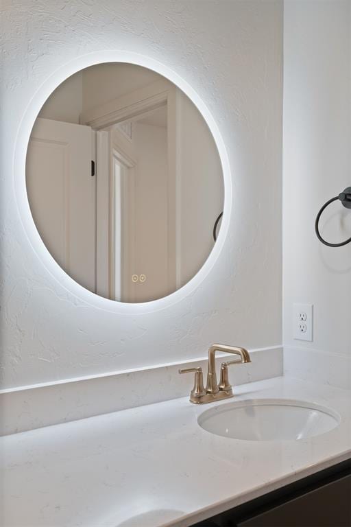 bathroom with a textured wall and vanity